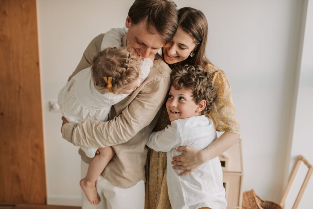 Husband and wife embracing their young children at home